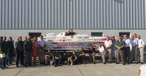 A group of people stand in front of a race boat