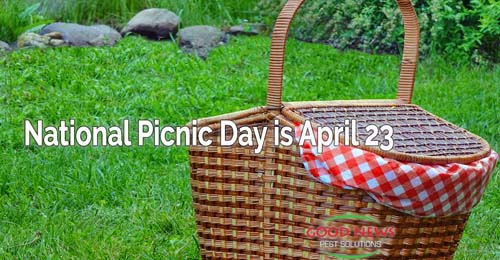 a picnic basket on the grass, with a red and white checkered cloth draped over its side.
